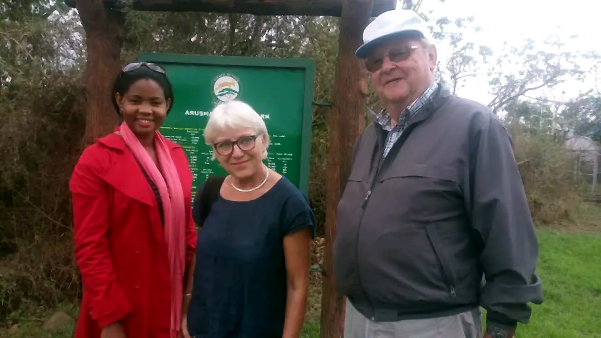 People standing at a conservation area sign in Arusha